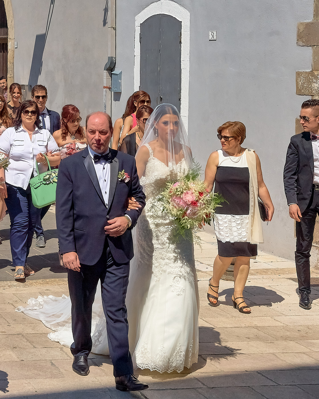 gli invitati seguono da vicino la sposa e il padre per l'ingresso in chiesa